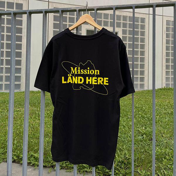 Schwarzes T-Shirt mit Mission LÄND HERE Aufdruck